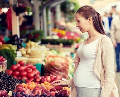 pregnant woman choosing food at street market