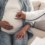 maternity insurance – pregnant woman having a prenatal checkup with a doctor using a stethoscope