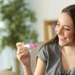 happy woman checking pregnancy test sitting