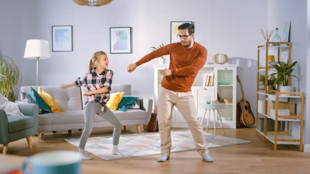 A father and his daughter dancing in the living room, concept of modern parenting