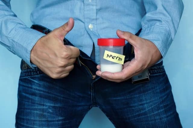 Sperm donation limit man holding sperm sample container with thumbs up