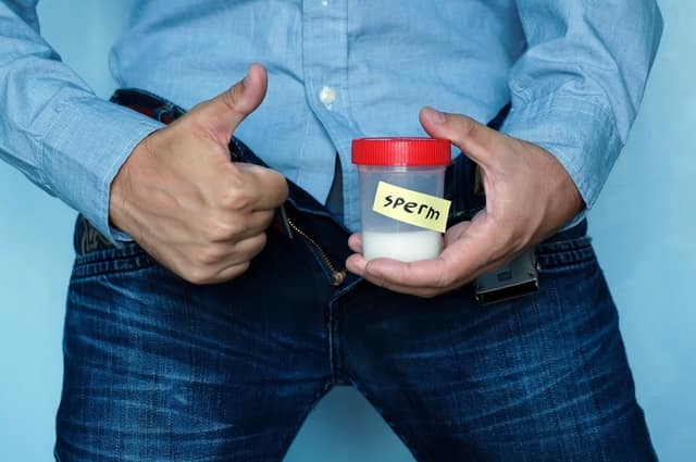 Sperm donation limit man holding sperm sample container with thumbs up
