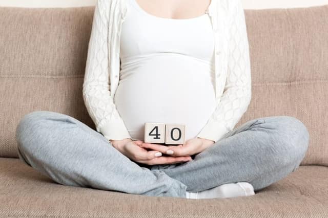 pregnancy over 40 showing pregnant woman holding number 40 on belly