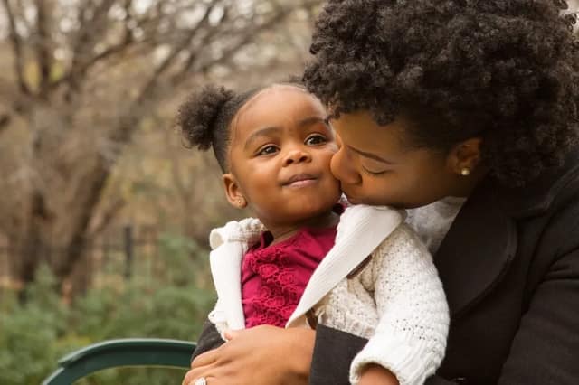 Sperm donor co-parent mother kissing her child showing bonding in a co-parenting situation