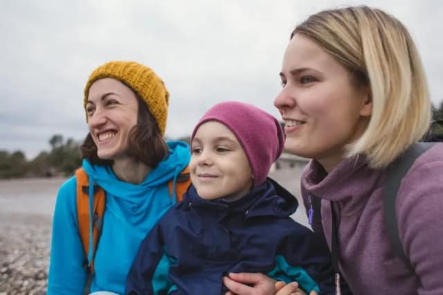 co parenting rules – two mothers and a smiling child enjoying an outdoor family moment