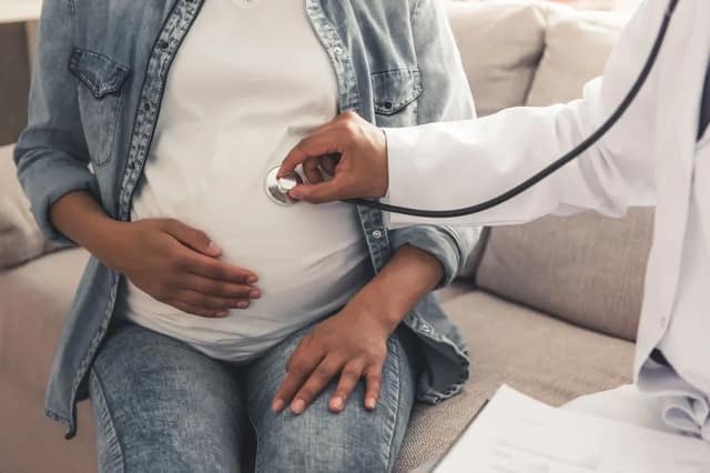 maternity insurance – pregnant woman having a prenatal checkup with a doctor using a stethoscope