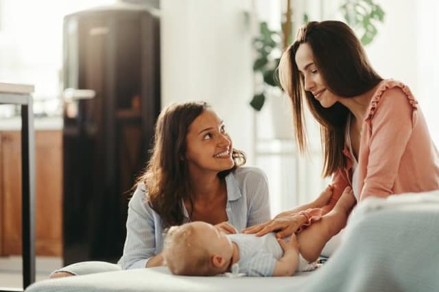 Homoparental family two women caring for a baby together at home