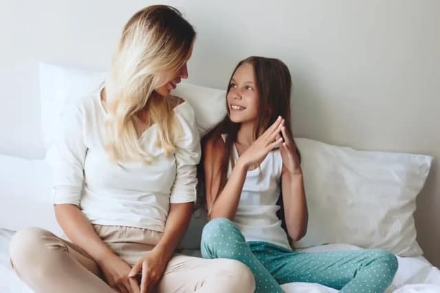 Donor conceived child mother and daughter talking together on a bed at home