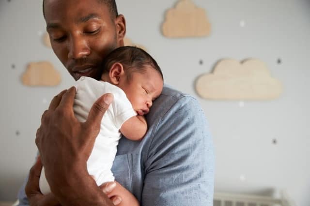 sleep training baby showing father holding newborn in nursery during bedtime routine