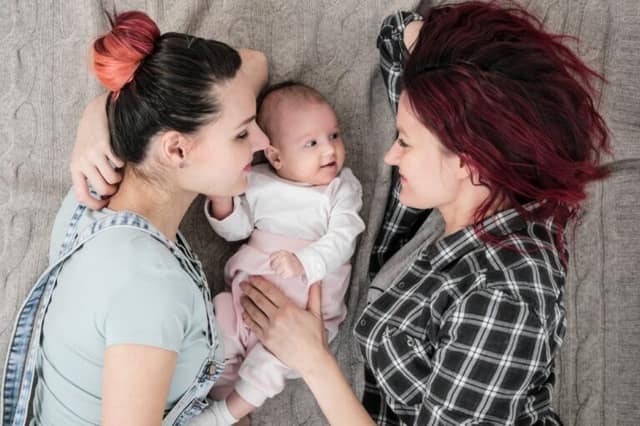 two young women casual clothes with a baby