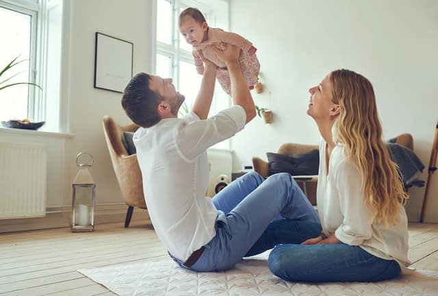happy couple playing with their baby at home, symbolizing becoming a parent