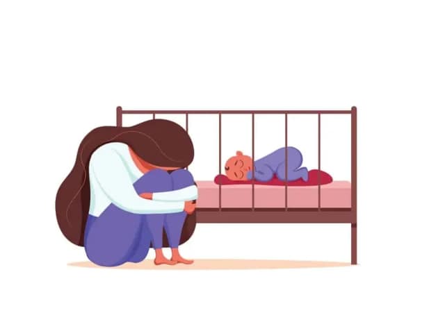 baby blues – sad and exhausted mother sitting beside a sleeping baby in a crib