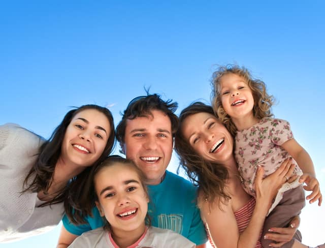Co parents smiling together with children outdoors under blue sky