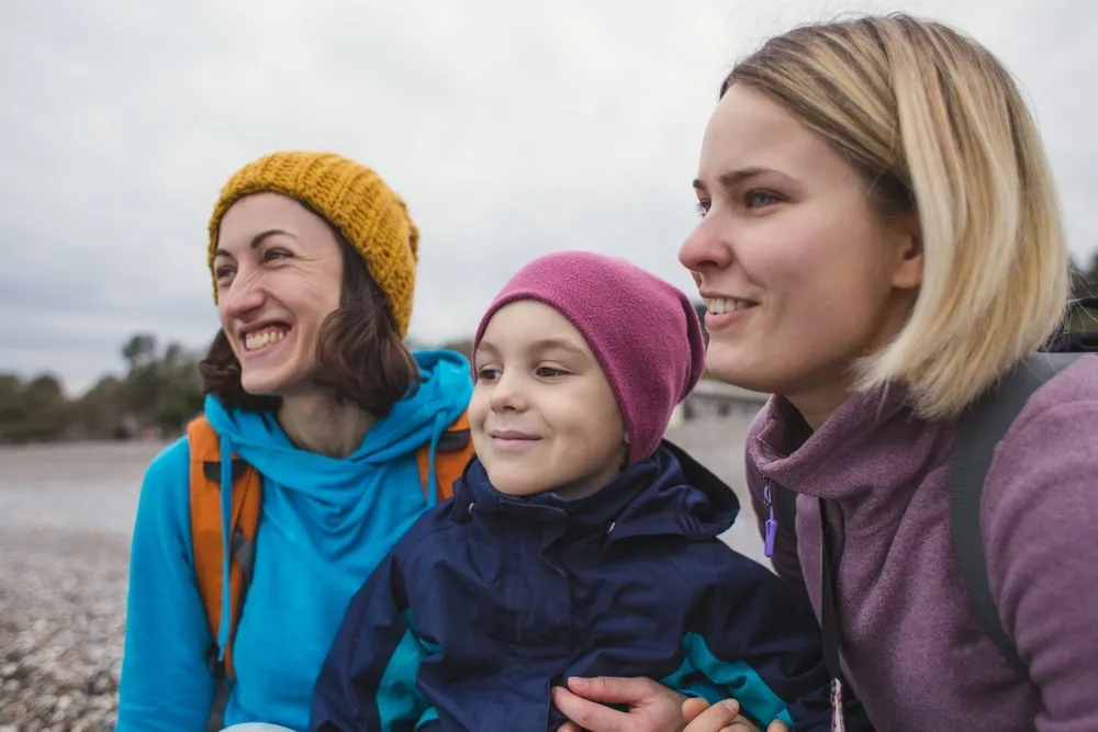 co parenting rules – two mothers and a smiling child enjoying an outdoor family moment