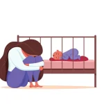 baby blues – sad and exhausted mother sitting beside a sleeping baby in a crib