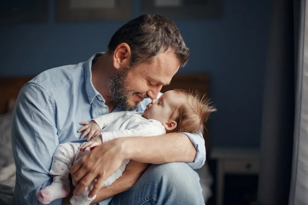 future dad – father holding and gently kissing his baby with love and care